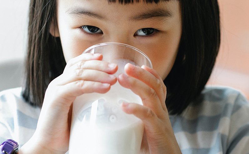 child drinking milk from glass“a